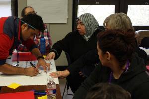 man writing on large sticky note with women at a group table